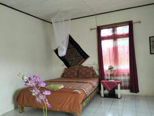 a bedroom with a bed and a window at Hobbit Hill in Ruteng