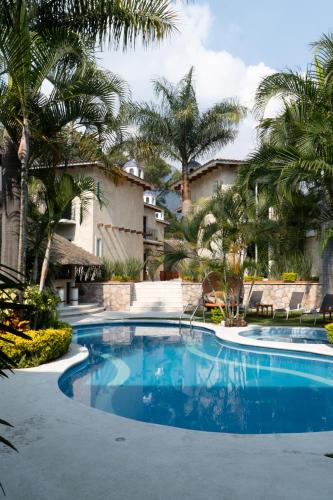 a swimming pool with palm trees and a building at Nequi Hotel Boutique in Tepoztlán