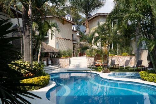 a swimming pool in a yard with palm trees at Nequi Hotel Boutique in Tepoztlán