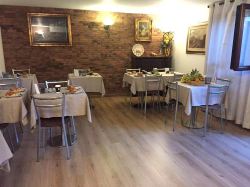 a restaurant with white tables and chairs and a brick wall at Relais Villa Rosa in Pero
