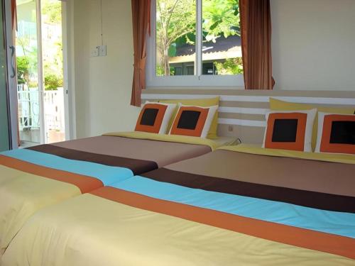 a bedroom with two beds with colorful pillows at Sea Beach Koh Larn 1 in Ko Larn