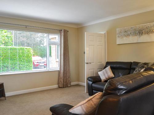 een woonkamer met een leren bank en een raam bij Oceans 44 in Sewerby