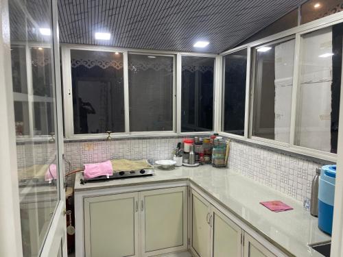 a kitchen with white cabinets and windows in a room at Countryside Retreat in Pune