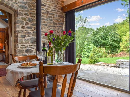 ein Tisch mit einer Vase mit Blumen und Weinflaschen in der Unterkunft Little Penquite in Landrake