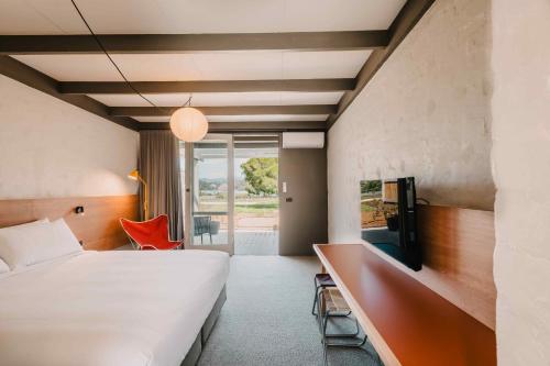 a bedroom with a bed and a desk with a tv at The Black Dolphin Motel in Merimbula