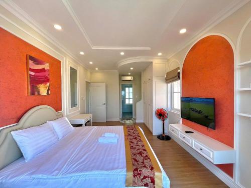 a bedroom with a large bed with an orange wall at Villa Giọt Nắng Phan Thiết in Phan Thiet
