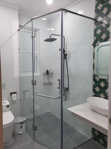 a bathroom with a glass shower with a toilet and a sink at Villa Giọt Nắng Phan Thiết in Phan Thiet