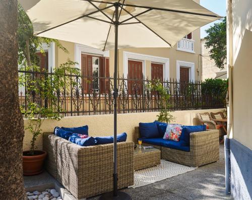 a patio with two wicker chairs and an umbrella at Villa Sanyan - Adults Only in Rhodes Town