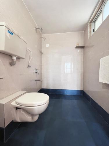 a bathroom with a white toilet and a blue floor at Shlok Villa in Bāmangaon