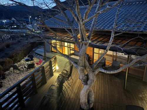 a tree on the deck of a building at 天然温泉と星空を楽しむ プライベートサウナ付き一棟貸しヴィラ in Ōkasho