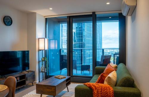 a living room with a couch and a large window at 33rd Floor Deluxe 2-BR Apartment - City Views, Pool, Hot Tub & Gym in Melbourne
