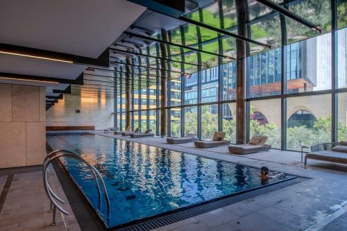 a large swimming pool in a building with windows at 33rd Floor Deluxe 2-BR Apartment - City Views, Pool, Hot Tub & Gym in Melbourne