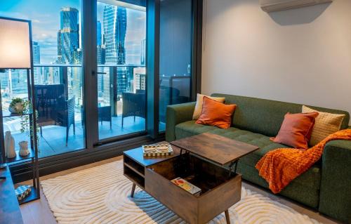 a living room with a green couch and a table at 33rd Floor Deluxe 2-BR Apartment - City Views, Pool, Hot Tub & Gym in Melbourne