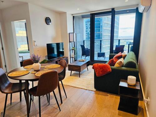 a living room with a couch and a table with chairs at 33rd Floor Deluxe 2-BR Apartment - City Views, Pool, Hot Tub & Gym in Melbourne