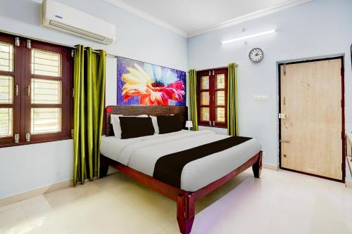 a bedroom with a bed and a painting on the wall at Super Hotel O Chittoor Railway Station Formerly Four Oaks in Chittoor