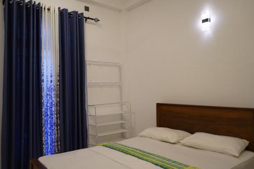 een slaapkamer met een bed en blauwe gordijnen bij Villa Hideout in Unawatuna