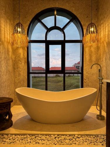 a large bath tub in front of a window at Villa Shugo Tenshi in Badung