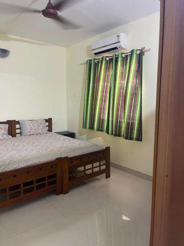 a bedroom with a bed and a green curtain at Sun & Sand Candolim Goa in Candolim