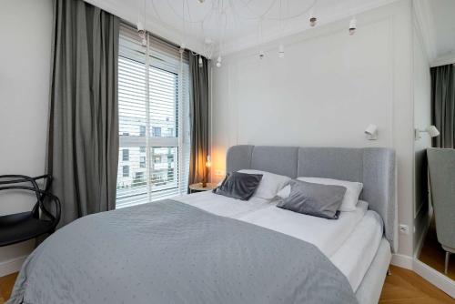 a bedroom with a large bed and a large window at Elegant Apartment with Parking Space and Balcony by Noclegi Renters in Gdynia