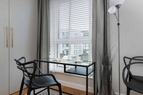 a table and chairs in a room with a window at Elegant Apartment with Parking Space and Balcony by Noclegi Renters in Gdynia
