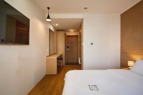 a bedroom with a white bed and a hallway at Hotel POCO Seongsu in Seoul