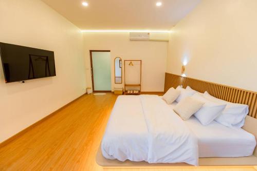 a bedroom with a large white bed and a flat screen tv at Yugen House - Yutaka in Nong Prue