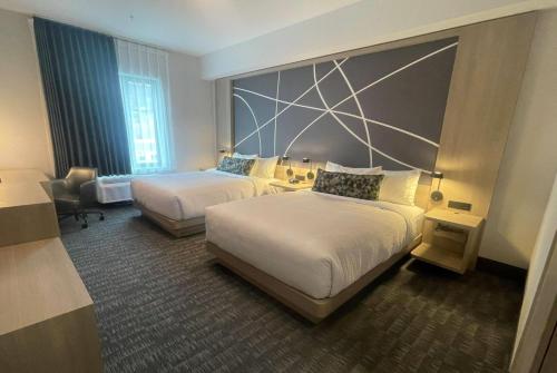 a hotel room with two beds and a chair at La Quinta Inn & Suites by Wyndham Kelowna BC in Kelowna