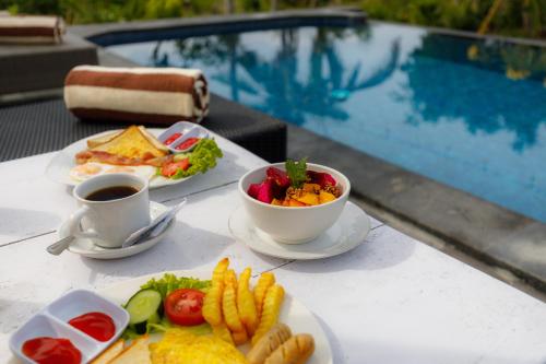 een tafel met borden eten en een kopje koffie bij Bunut Bungalow in Nusa Penida