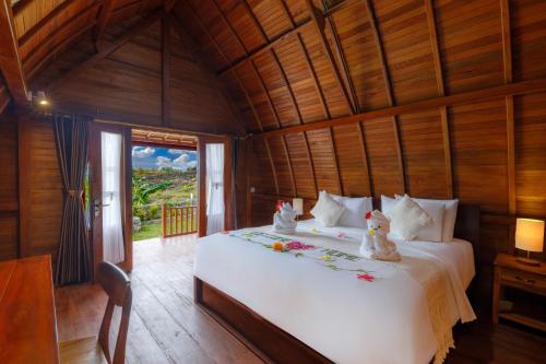 een slaapkamer met een wit bed in een houten kamer bij Bunut Bungalow in Nusa Penida