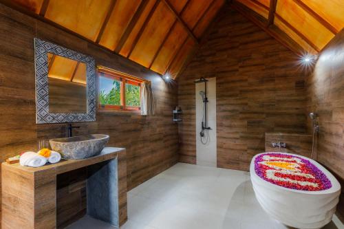 een badkamer met een groot bad en een wastafel bij Bunut Bungalow in Nusa Penida
