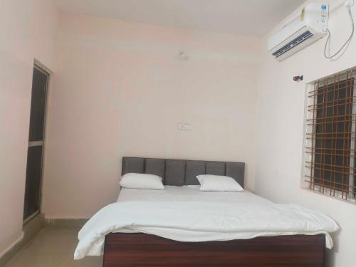 una camera da letto con un letto con lenzuola bianche e una finestra di Hotel O Sunset a Bilaspur