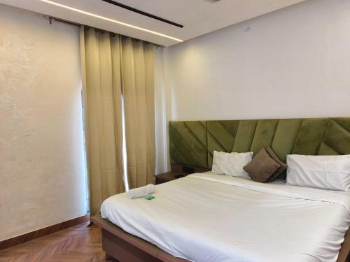 een slaapkamer met een groot wit bed met een groen hoofdeinde bij Hotel O Sunrise View in Phagwara