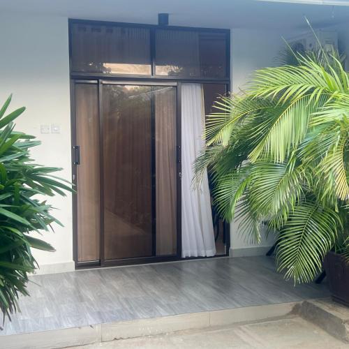 une porte vitrée dans un bâtiment avec deux plantes dans l'établissement PONTOOn STUDIO, à Mombasa