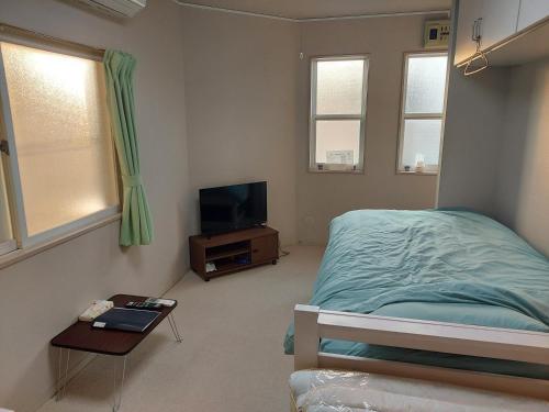 una camera da letto con un letto e una TV a schermo piatto di トリトン茶屋町#101#102 ad Aomori