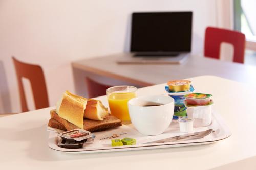 a breakfast tray with toast and coffee and orange juice at Premiere Classe Dunkerque Saint Pol Sur Mer in Saint-Pol-sur-Mer