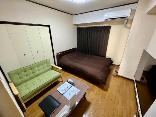 ein kleines Zimmer mit einem grünen Sofa und einem Tisch in der Unterkunft Stay Plus Sophia in Utsunomiya