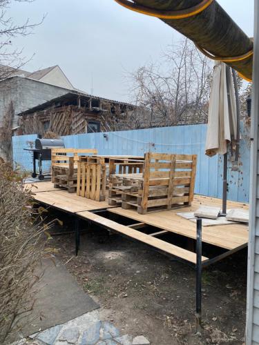 a wooden bench with a table and an umbrella at Leonovs in Almaty