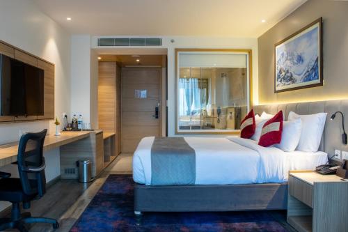 Una habitación de hotel con una cama, un escritorio y un televisor. en Best Western Plus Kathmandu Hotel, en Katmandú