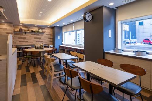 ein Restaurant mit Tischen und Stühlen und einer Uhr an der Wand in der Unterkunft Comfort Hotel Hakodate in Hakodate