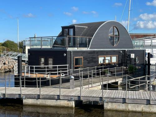 een woonboot aangemeerd op een dok in het water bij 5-star houseboat of 125 m2 with its own bathing jetty in Nykøbing Sjælland