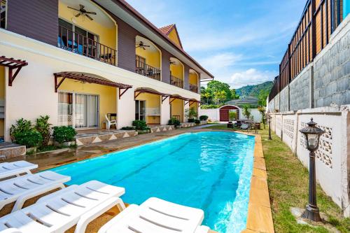 a pool in the backyard of a house with white chairs at Chernin Apartment Suites, Rawai in Ban Saiyuan (1)