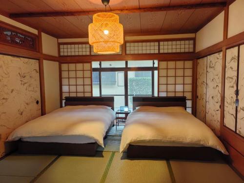 two beds in a bedroom with a chandelier at 山海温泉別荘Hot Spring Villa in Beppu