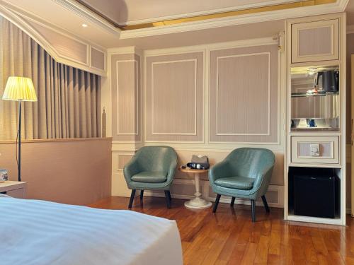 a bedroom with two chairs and a table and a bed at Finders Hotel Hualien Station in Hualien City