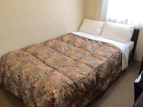a bed in a room with a pillow and a blanket at Hotel Crown Hills Toyama in Toyama