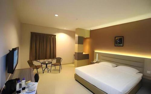 a hotel room with a bed and a table and chairs at Lovina Inn Hotel Batam in Batam Center