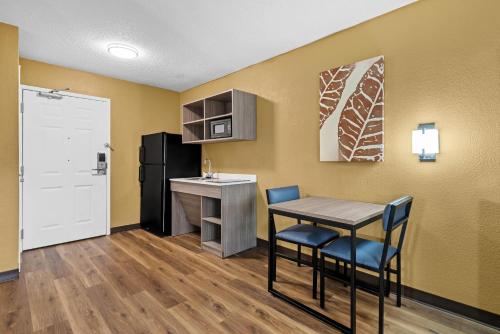 une petite cuisine avec une table et un réfrigérateur noir. dans l'établissement Suburban Studios Charlotte - Executive Park, à Charlotte