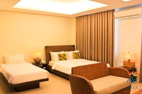 a hotel room with two beds and a chair at Azia Suites and Residences in Cebu City