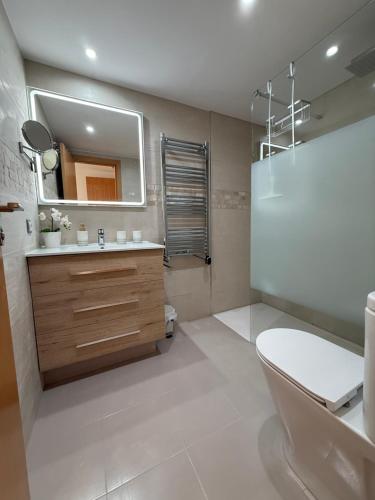 een badkamer met een wastafel, een toilet en een spiegel bij Casa Laguna in Casares
