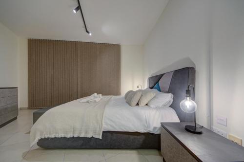 a bedroom with a large bed and a dresser at Bright 1BR in the Heart of St Julians in St. Julianʼs