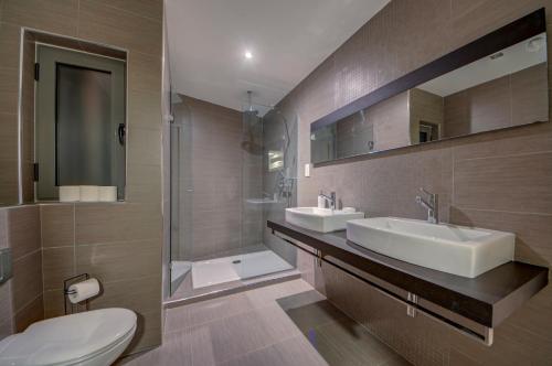 a bathroom with two sinks and a shower and a toilet at Bright 1BR in the Heart of St Julians in St. Julianʼs